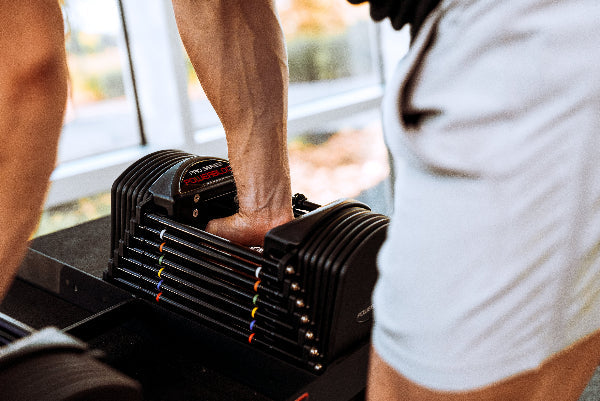 PowerBlock Commercial Pro 50 adjustable dumbbells and Pro Rack stand in a commercial training space