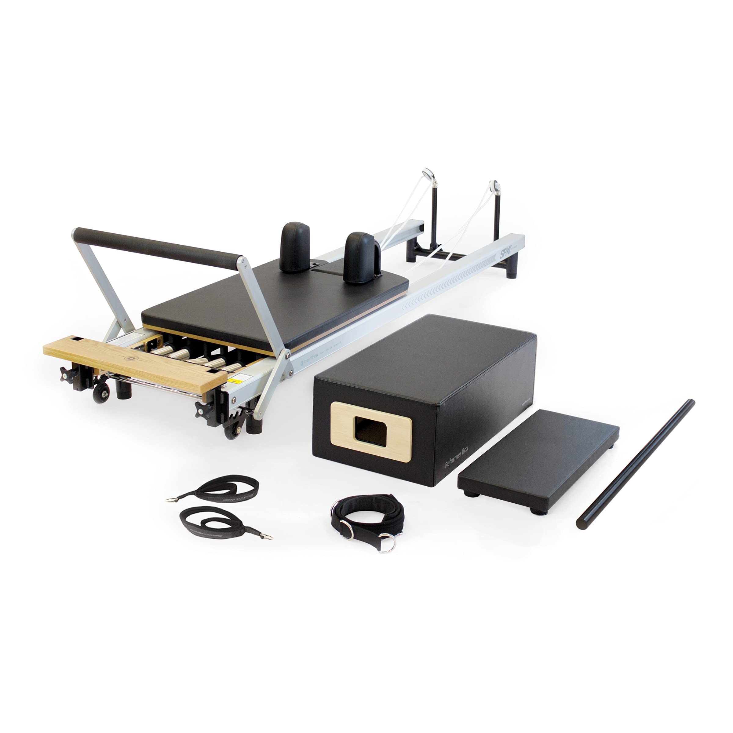 A Pilates reformer machine with a black padded platform, resistance cords, adjustable bar, a large black foam block, a smaller rectangular pad, straps, and a pole, all set against a white background.