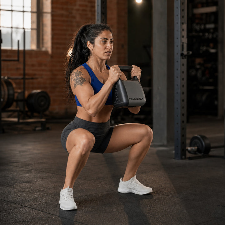 Woman performing a goblet squat with the PowerBlock adjustable kettlebell