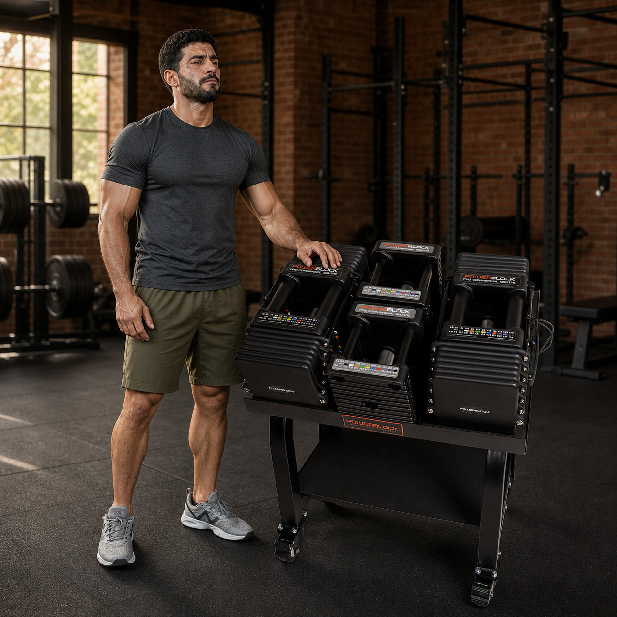 Man standing beside the PowerBlock Commercial Pro 125 adjustable dumbbell set and rolling stand