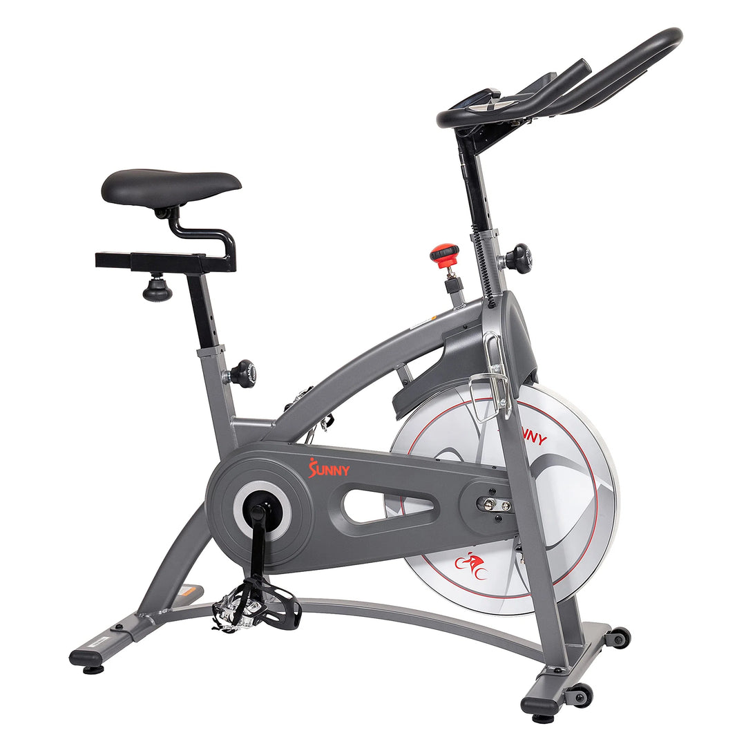 The Sunny Health & Fitness Synergy Series Magnetic Indoor Cycling Exercise Bike features a black seat and handlebar, silver frame, red flywheel, and adjustable knobs for a tailored workout. The Sunny brand is prominently displayed in bold red on the frame.