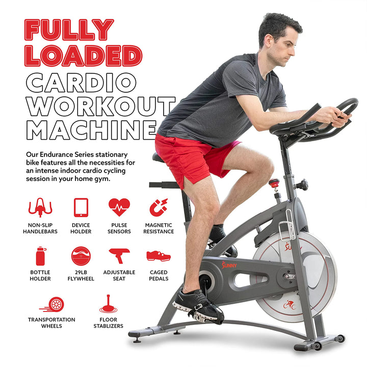 A man in athletic wear rides the Sunny Health & Fitness Synergy Series Magnetic Indoor Cycling Exercise Bike, featuring non-slip handlebars, a device holder, a bottle holder, a 29lb flywheel, an adjustable seat, caged pedals, and magnetic resistance for an intense fitness experience.