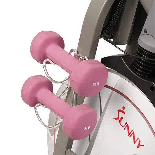 Two pink 5 lb dumbbells are securely mounted on the Sunny Health & Fitness Synergy Series Magnetic Indoor Cycling Exercise Bike. The sleek gray and white bike features Sunny in red on the wheel cover, enhancing its stylish look.