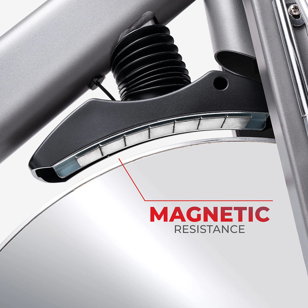 A close-up showcases the sleek magnetic resistance system of the Sunny Health & Fitness Synergy Series Magnetic Indoor Cycling Exercise Bike, featuring a black magnetic component against a metallic surface labeled MAGNETIC RESISTANCE in bold red, epitomizing advanced design and functionality.