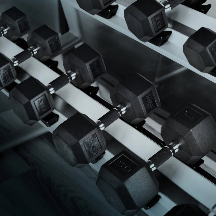 A rack displays Yes4All Rubber Grip Encased Hex Dumbbells by Yes4All, with a solid cast-iron core and rubber grip, neatly arranged on a metal stand. The premium rubber coating ensures durability, contrasting strikingly with the dark floor in the background.